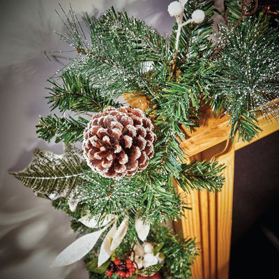 Decorated Christmas Garland with Pine Cones and Berries on wooden mantel piece