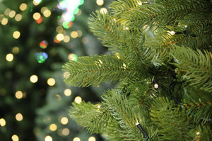 Pine needle branches of artificial green Christmas tree with fairy lights 