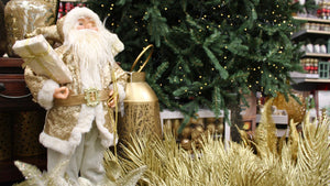 Gold Santa Claus holding gift in front of Christmas Tree with gold Stems