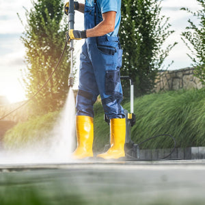 man wearing wellies while power hosing driveway
