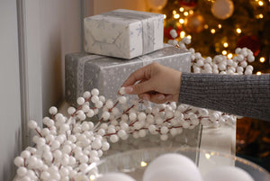 White Berry Garland with silver wrapped Christmas gifts and lit up Christmas Tree in the background