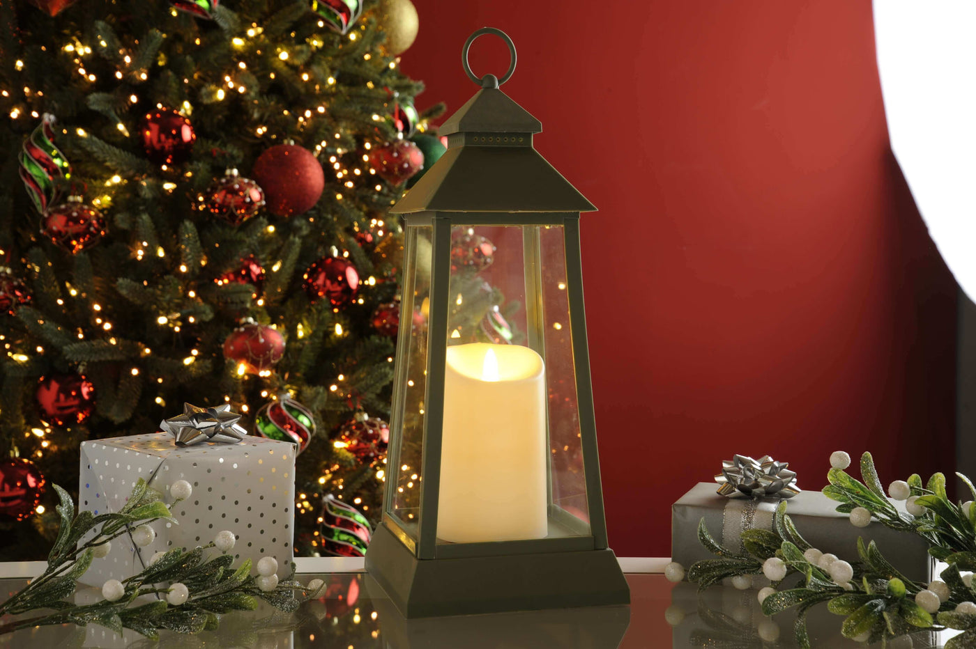 Lantern with candle on table with Christmas Tree and gifts in the background