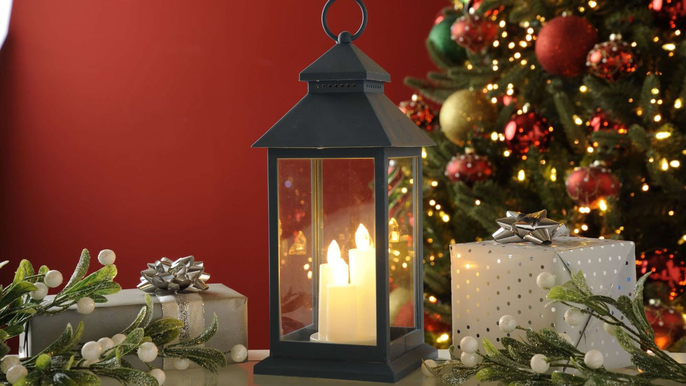 Christmas Lantern with 3 flickering candles with gifts in front of elegant Christmas Tree 