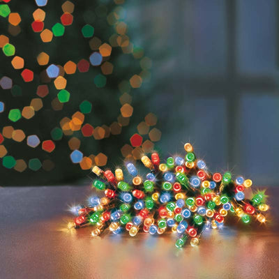 Multi coloured LED string Christmas lights on table with Christmas Tree in the background