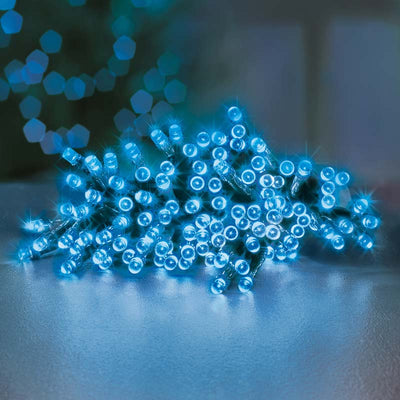 100 Battery Operated Blue TimeLights with Green Cable on table with Christmas tree lit in the background